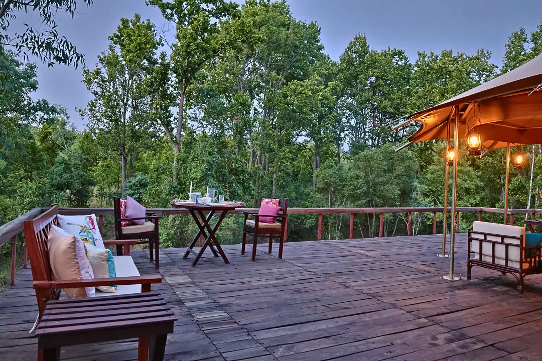 The Chief's Tent deck at dusk, lanterns lit, with chairs facing the forest