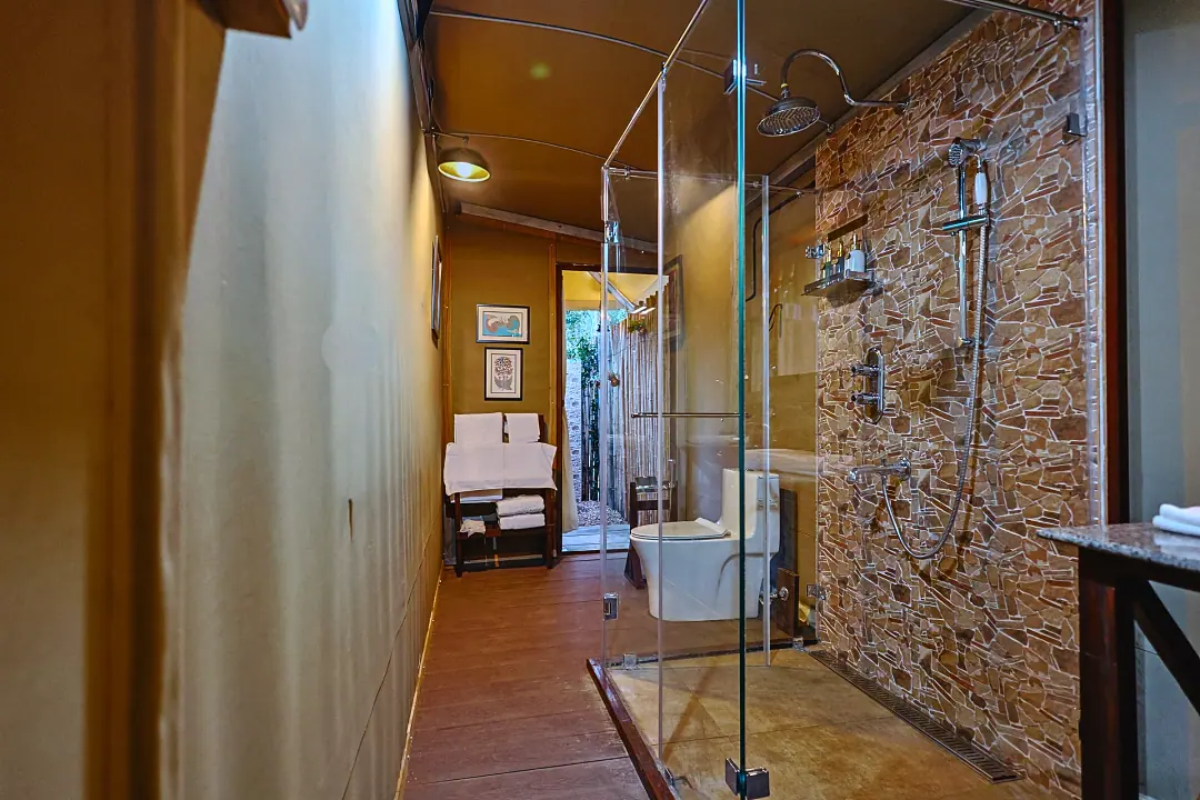 The King's Tent bathroom with a glass shower and stone wall