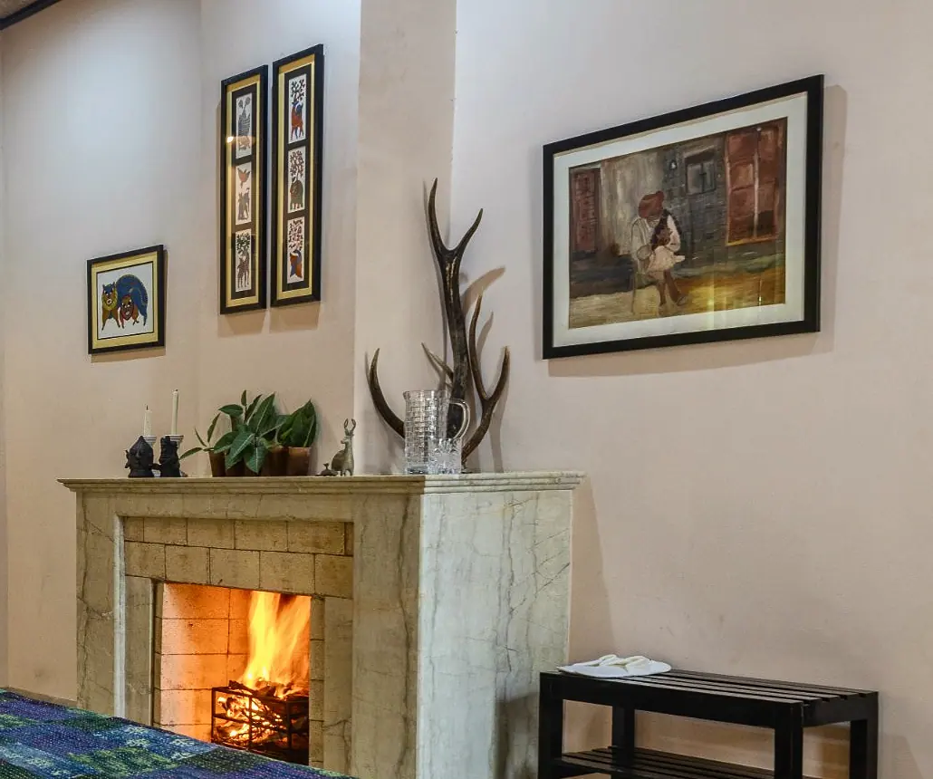 A Victorian fireplace, lit, with antlers on the mantel
